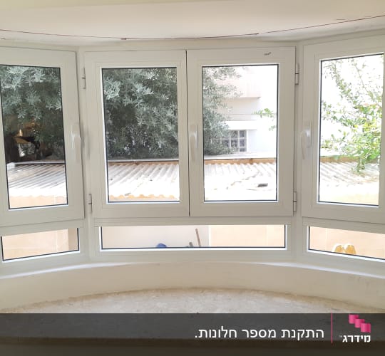חלונות ציר מאלומיניום לבן במבנה קשתי מעל אדן שיש